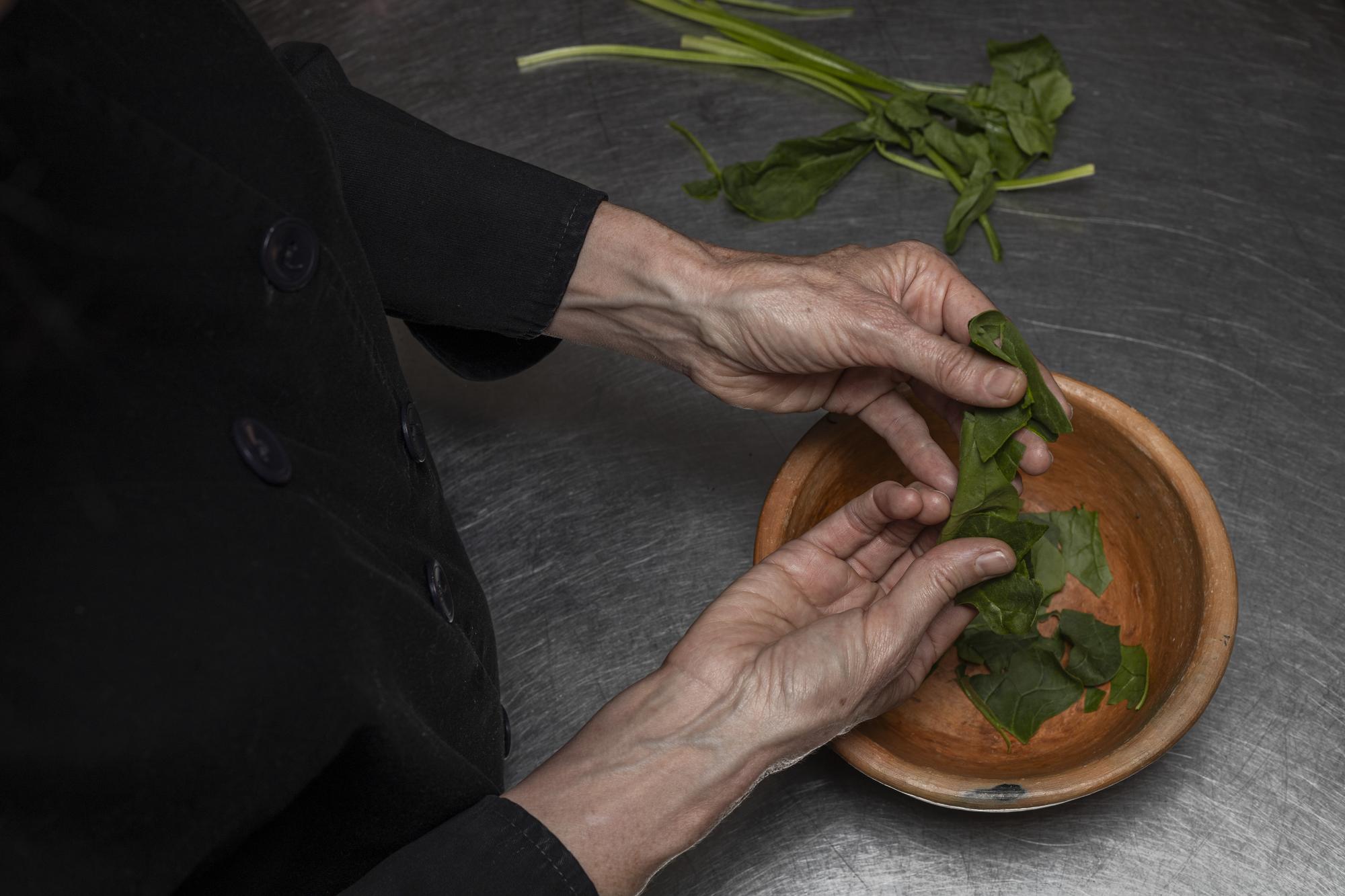 Chef plating at counter with herbs and clay plates